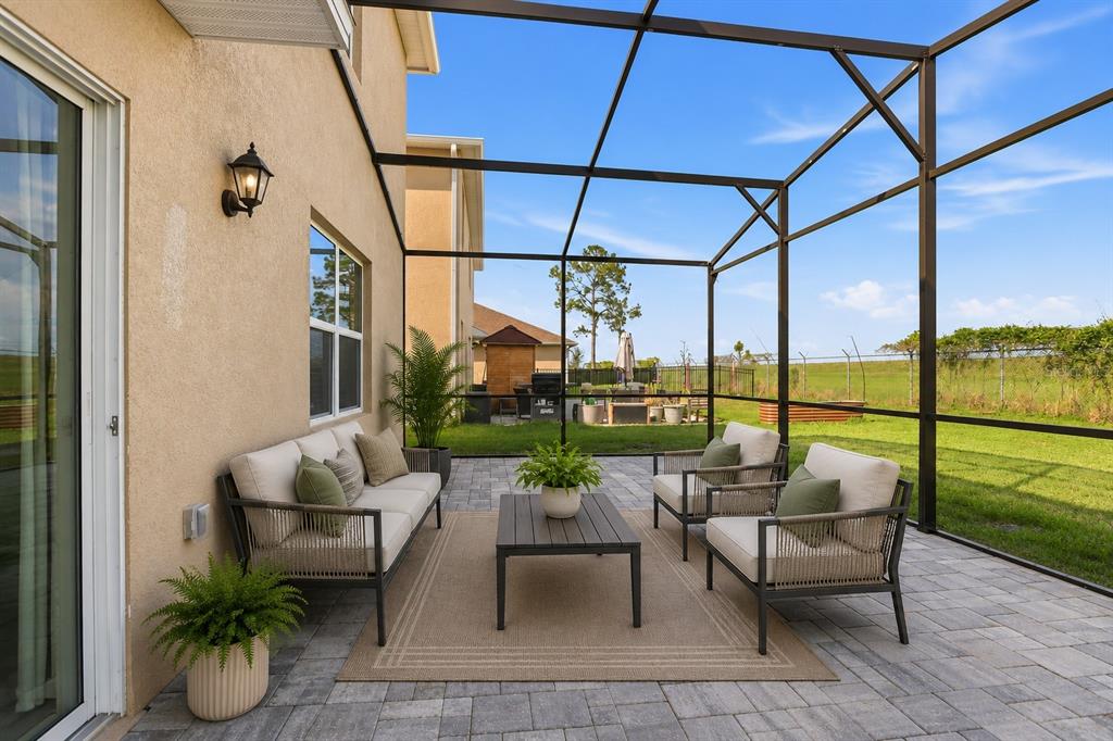 A screened-in patio features outdoor furniture on a paved floor overlooking a grassy yard — 531 LAZIO CIRCLE, DEBARY, FL