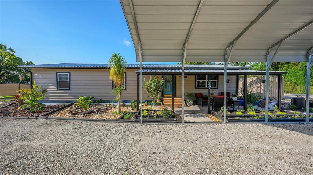 A single-story house with tan siding and a metal carport over a gravel driveway — 34647 S HAINES CREEK ROAD, LEESBURG, FL