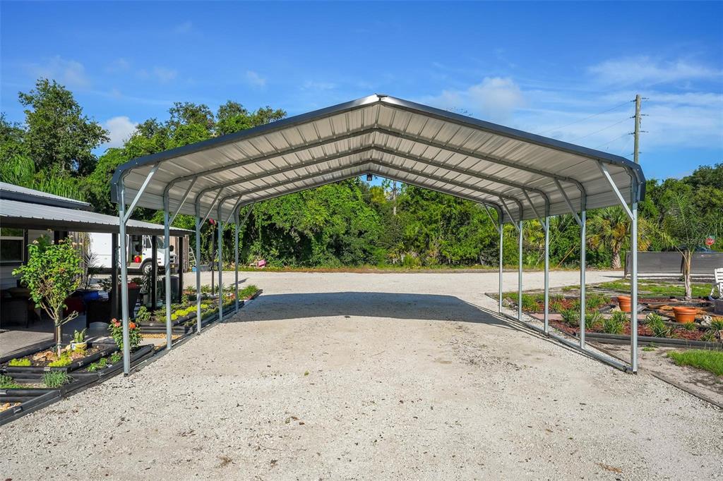 A metal carport stands over a gravel driveway in a sunny outdoor area — 34647 S HAINES CREEK ROAD, LEESBURG, FL