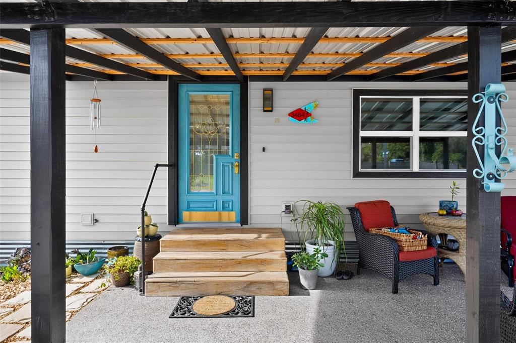A covered porch features a bright blue front door, wooden steps, and outdoor seating — 34647 S HAINES CREEK ROAD, LEESBURG, FL