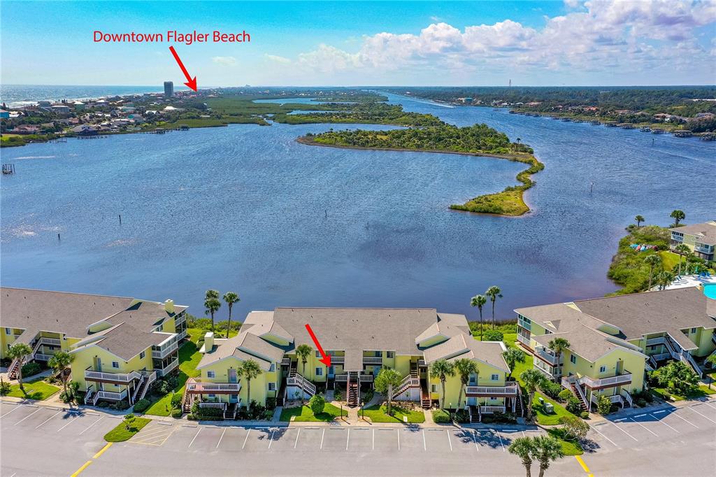 An aerial view shows yellow multi-story apartment buildings situated along a large body of water — 504 OCEAN MARINA DRIVE UNIT 504, FLAGLER BEACH, FL