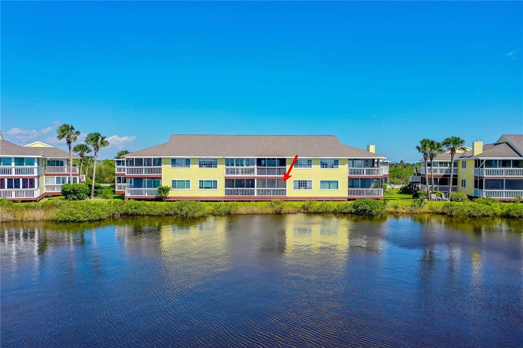 An exterior view of a yellow multi-story apartment building overlooking a pond — 504 OCEAN MARINA DRIVE UNIT 504, FLAGLER BEACH, FL