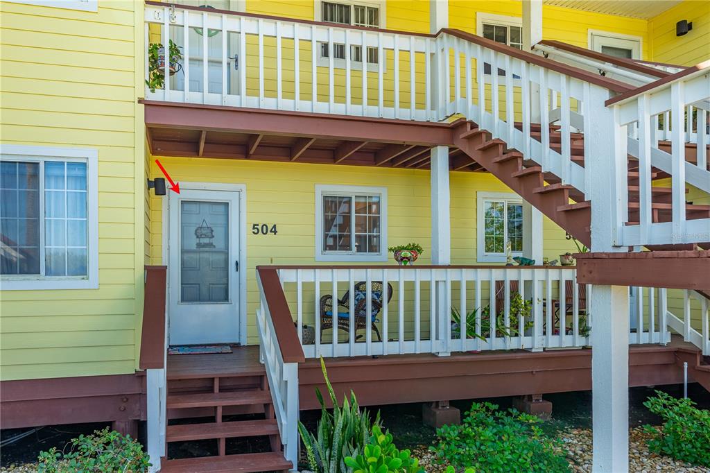 The exterior of a yellow two-story building features a white front door labeled 504 — 504 OCEAN MARINA DRIVE UNIT 504, FLAGLER BEACH, FL