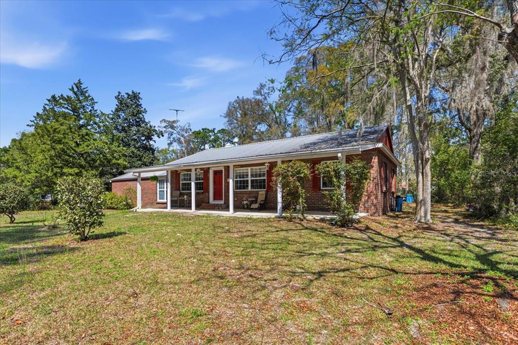 A single-story brick house with a metal roof and a covered front porch — 24224 NW 188TH AVENUE, HIGH SPRINGS, FL
