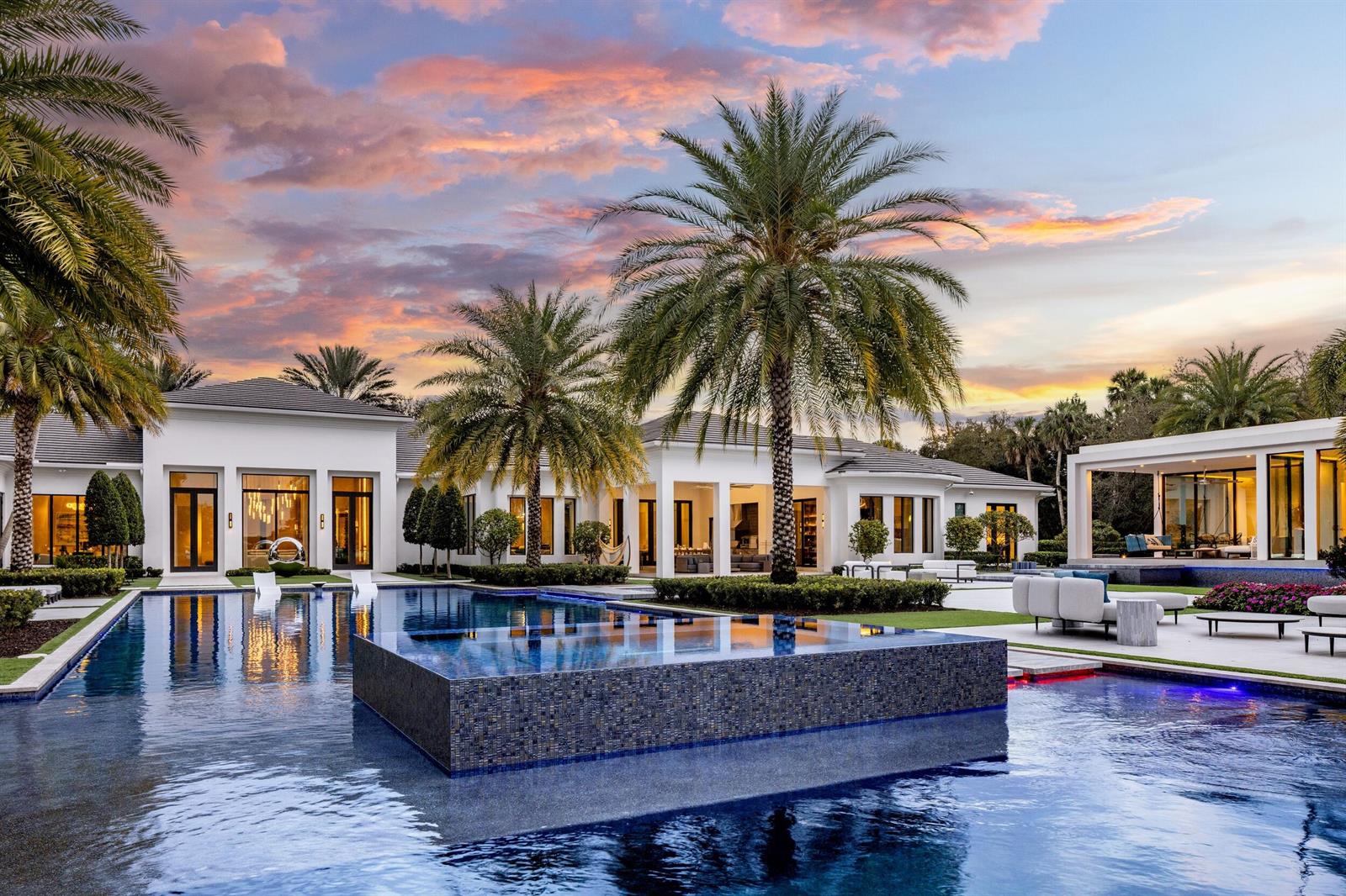 A modern white house with a large infinity pool and palm trees at sunset — 16191 Quiet Vista Circle, Delray Beach FL 33446, DELRAY BEACH, FL