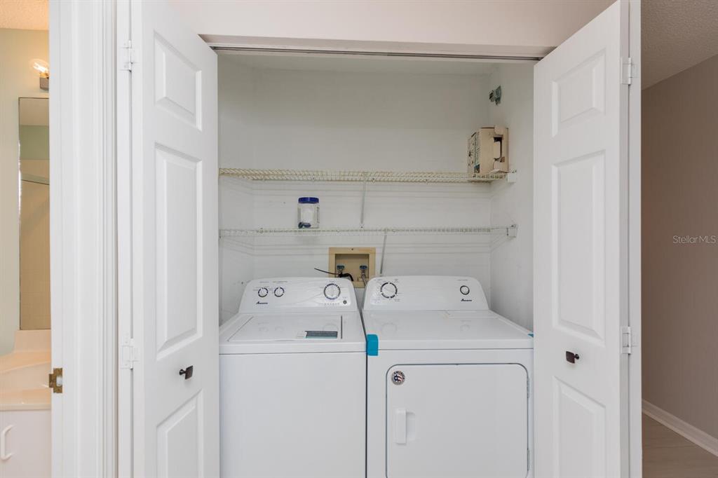 A laundry closet contains a white top-loading washing machine and a matching dryer — 104 SURFVIEW DRIVE UNIT 1406, PALM COAST, FL