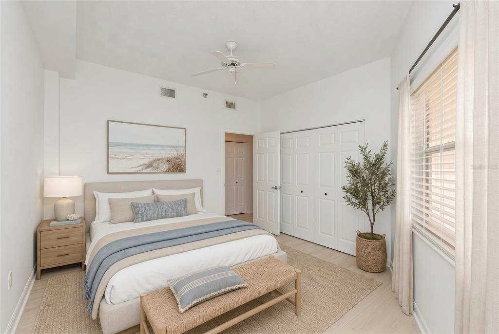 A bedroom features a queen bed, a wooden bench, a potted plant, and white walls — 104 SURFVIEW DRIVE UNIT 1406, PALM COAST, FL