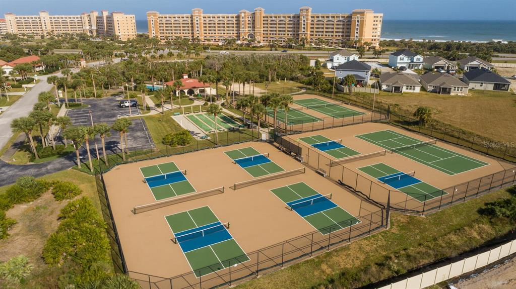An aerial view shows multiple pickleball courts, a parking lot, and a large beachfront resort — 104 SURFVIEW DRIVE UNIT 1406, PALM COAST, FL