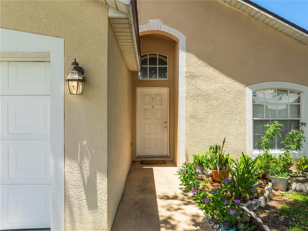 The exterior view shows a beige stucco home entrance with a white door and landscaping — 2944 COOL BREEZE CIRCLE, ST CLOUD, FL