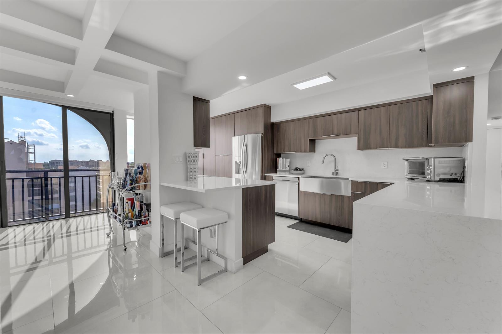 A modern kitchen features dark wood cabinetry, white quartz countertops, and a balcony with views — 7178 Promenade Drive # 801b, Boca Raton FL 33433, BOCA RATON, FL