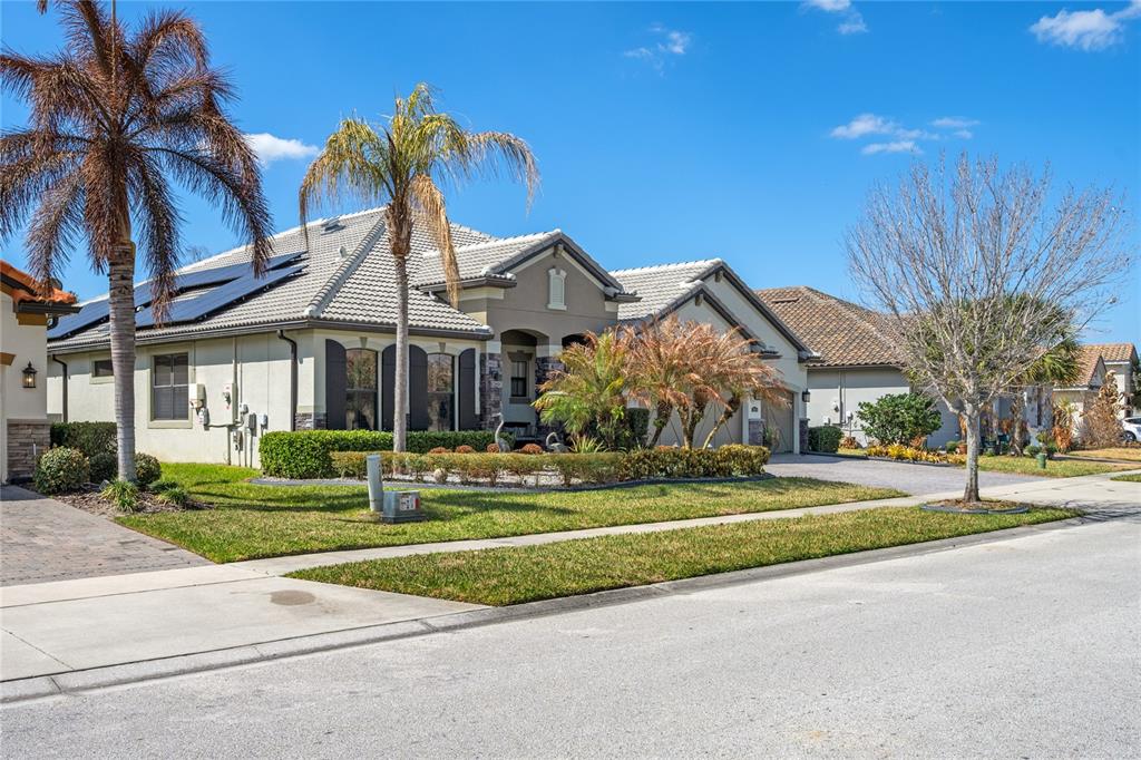 A single-story suburban house with a tiled roof, solar panels, and a landscaped front yard — 3816 BOWFIN TRAIL, KISSIMMEE, FL