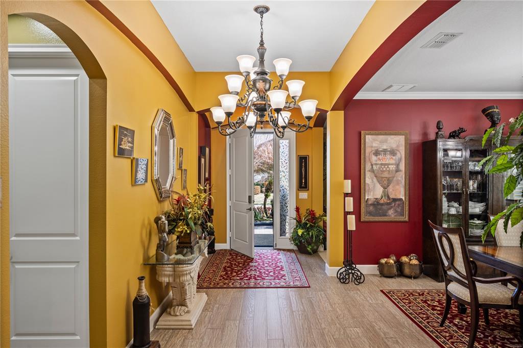 An entryway with a chandelier, yellow and red walls, and wood-look tile flooring — 3816 BOWFIN TRAIL, KISSIMMEE, FL