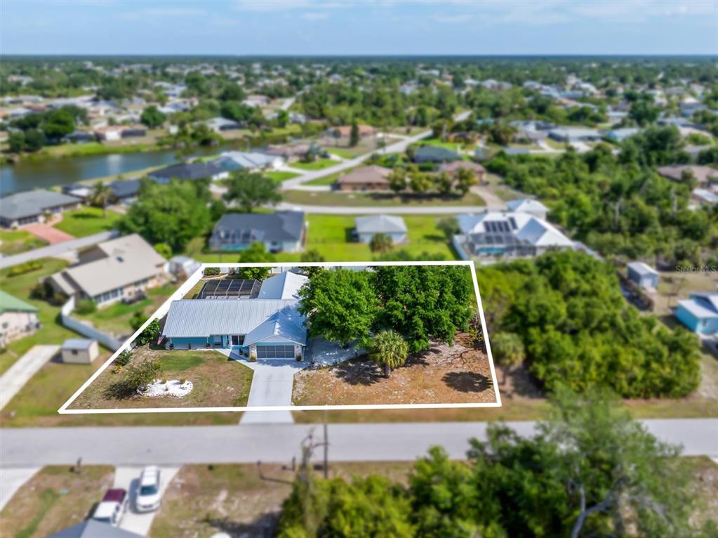 A single-story house with a teal exterior, white metal roof, and a concrete driveway — 10104 RAFFERTY AVENUE, ENGLEWOOD, FL