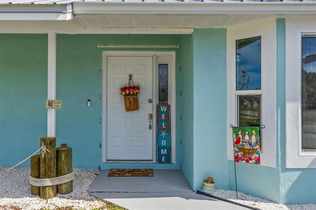A beige storage shed stands in a grassy backyard next to a light blue house — 10104 RAFFERTY AVENUE, ENGLEWOOD, FL