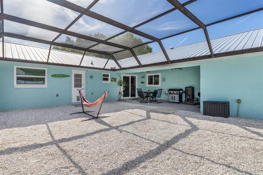 A screened-in patio features a gravel floor, a hammock, and a small outdoor dining area — 10104 RAFFERTY AVENUE, ENGLEWOOD, FL