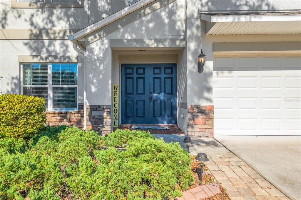 The exterior of a house features a blue double front door and a garage — 18345 FISH LOOP, LAND O LAKES, FL