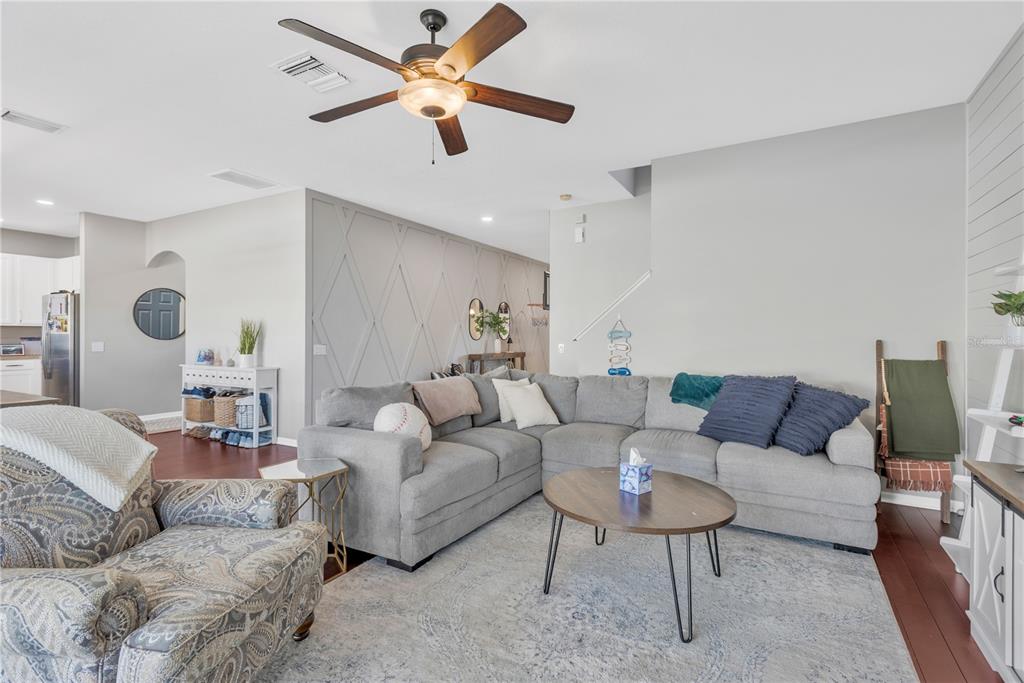A living room features a grey sectional sofa, a round coffee table, and patterned armchair — 18345 FISH LOOP, LAND O LAKES, FL