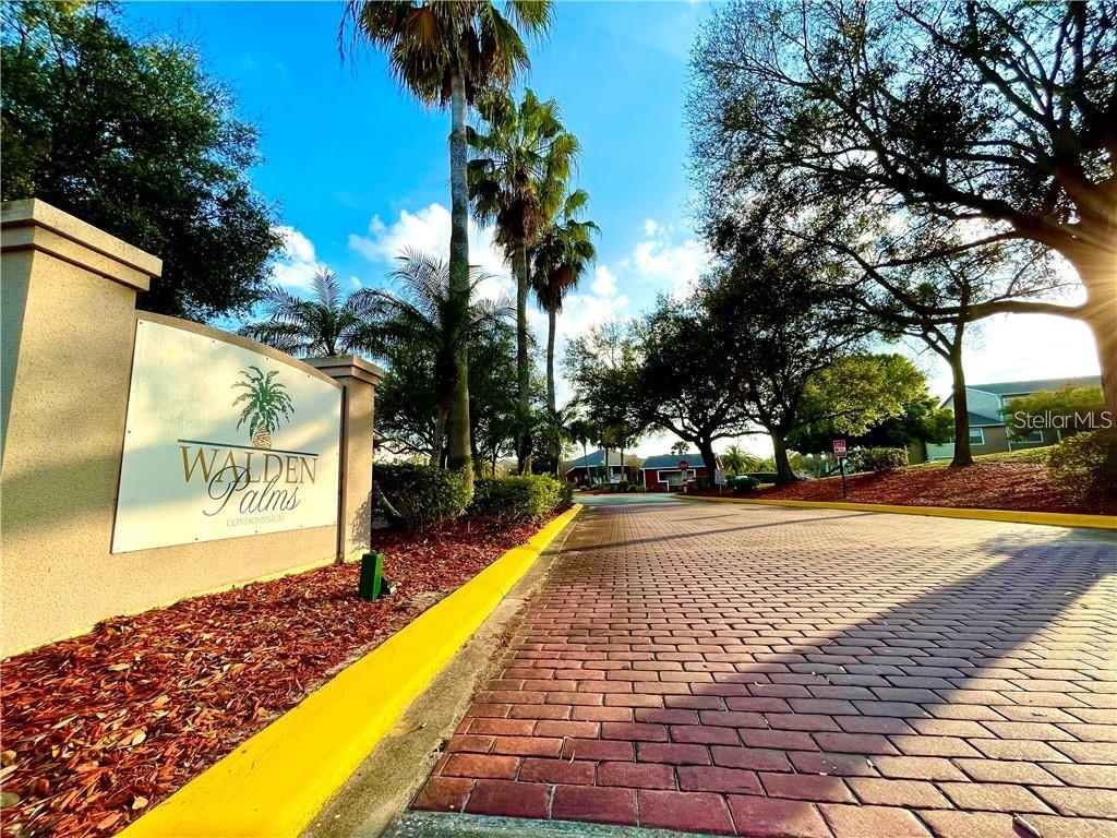 A brick driveway leads to the entrance sign of the Walden Palms condominium complex — 4756 WALDEN CIRCLE UNIT 11, ORLANDO, FL
