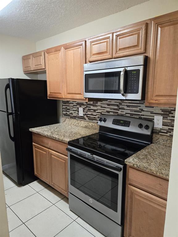 A kitchen features light wood cabinets, granite countertops, stainless steel appliances, and a tiled backsplash — 4756 WALDEN CIRCLE UNIT 11, ORLANDO, FL