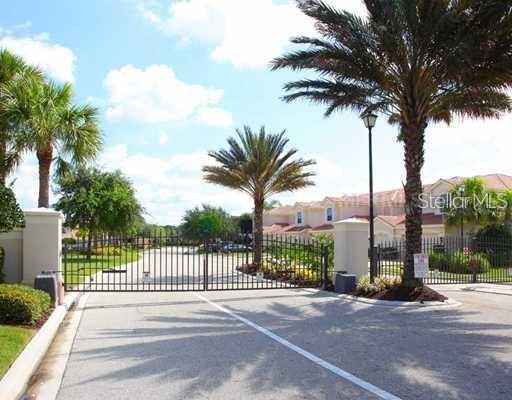 A gated entrance with palm trees leads to a residential community with multi-story buildings — 4484 STREAMSIDE COURT UNIT 1503, SARASOTA, FL