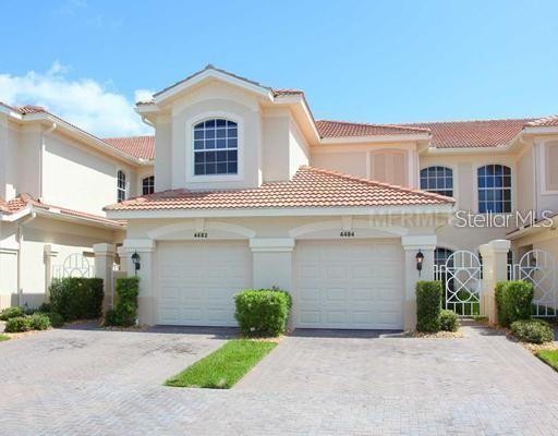 A two-story townhouse with a beige stucco exterior, two garage doors, and a tiled roof — 4484 STREAMSIDE COURT UNIT 1503, SARASOTA, FL