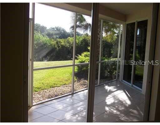 A screened-in patio with light-colored tile flooring overlooks a grassy yard and trees — 4484 STREAMSIDE COURT UNIT 1503, SARASOTA, FL