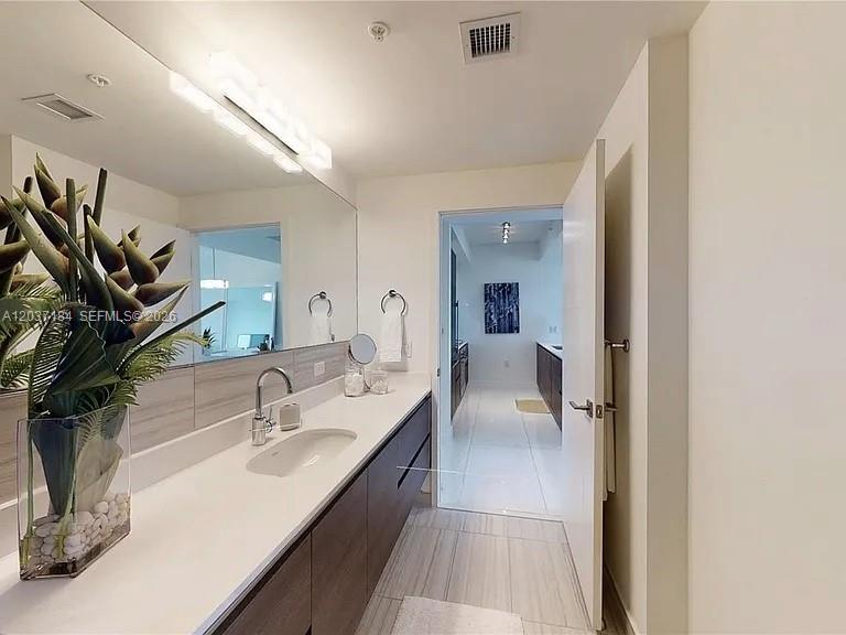A modern bathroom features a long vanity with a sink, large mirror, and tiled flooring — 301 Altara Ave # 527, Coral Gables FL 33146, CORAL GABLES, FL