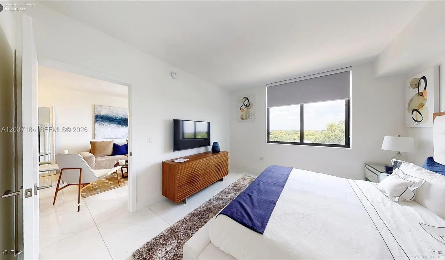 A bedroom with white tile floors, a wooden dresser, and a view of trees outside — 301 Altara Ave # 527, Coral Gables FL 33146, CORAL GABLES, FL