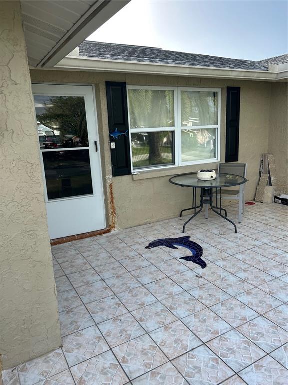 A tiled patio features a small round table, a dolphin mosaic, and a glass door — 13725 PLUMOSA AVENUE, HUDSON, FL