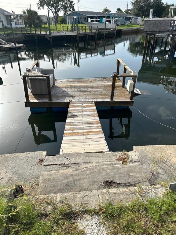 A wooden floating dock extends from concrete steps into a canal with other boat docks — 13725 PLUMOSA AVENUE, HUDSON, FL