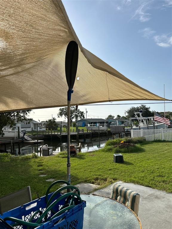 A tan shade sail is propped up by a paddle over a backyard patio area — 13725 PLUMOSA AVENUE, HUDSON, FL