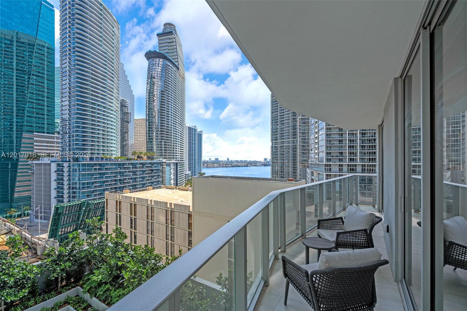 A balcony with two chairs overlooks a city skyline and a body of water — 77 SE 5 # 1601, Miami FL 33131, MIAMI, FL