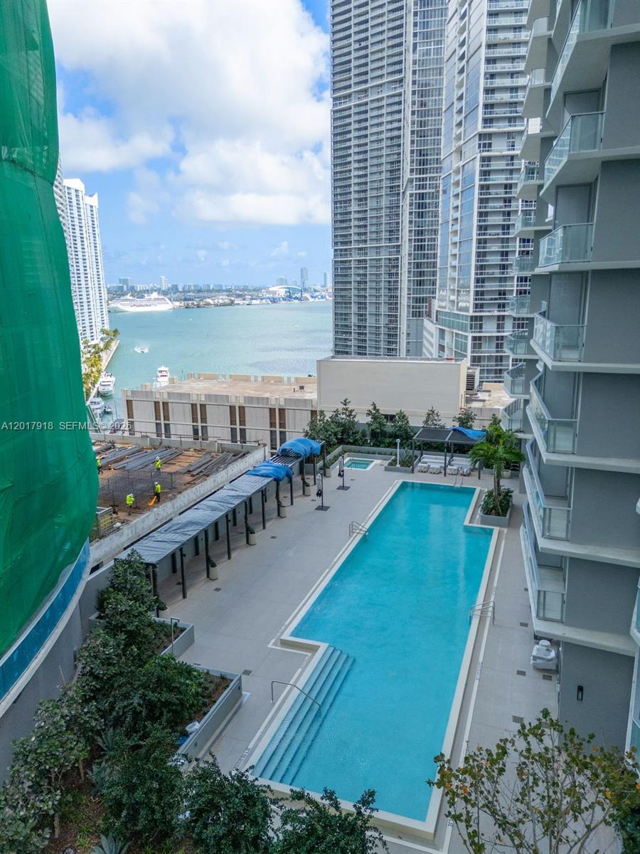 An elevated view of a swimming pool deck overlooking a bay with high-rise buildings — 77 SE 5 # 1601, Miami FL 33131, MIAMI, FL