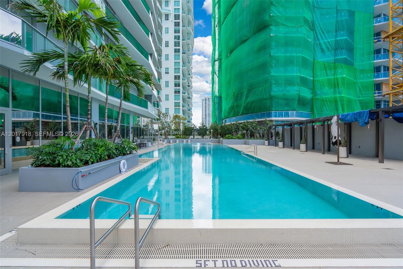 A rectangular outdoor swimming pool is situated between two tall residential buildings — 77 SE 5 # 1601, Miami FL 33131, MIAMI, FL