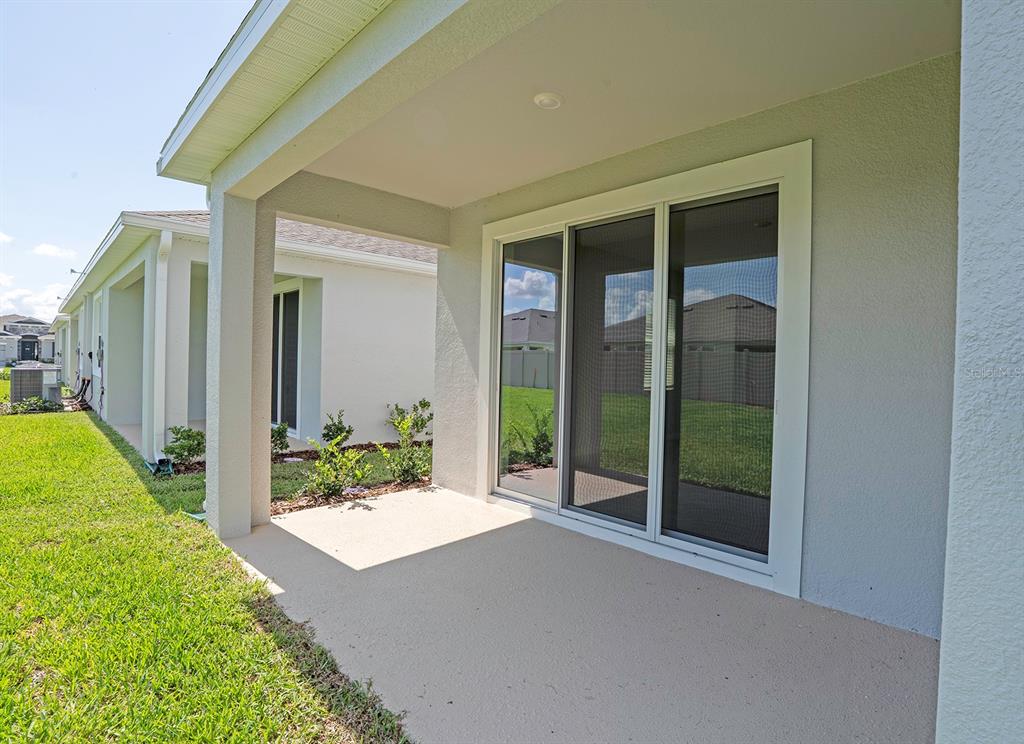 A covered concrete patio with a sliding glass door overlooks a grassy backyard — 4010 WESTWOOD FIELDS LOOP, PLANT CITY, FL