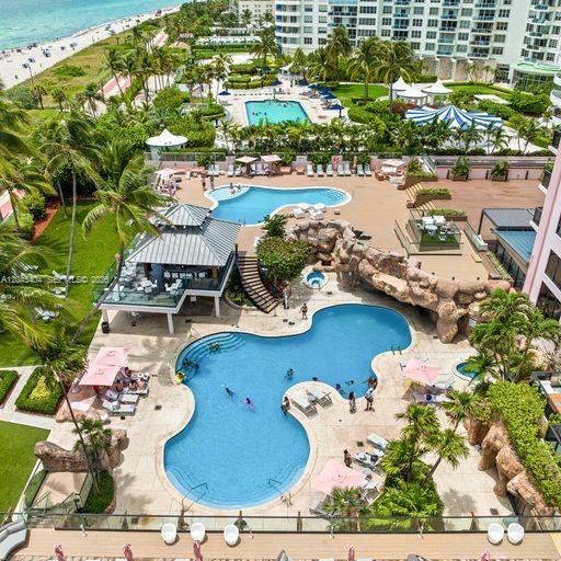 An aerial view of a resort-style swimming pool complex with palm trees and beach access — 5225 Collins Ave # 1117, Miami Beach FL 33140, MIAMI BEACH, FL