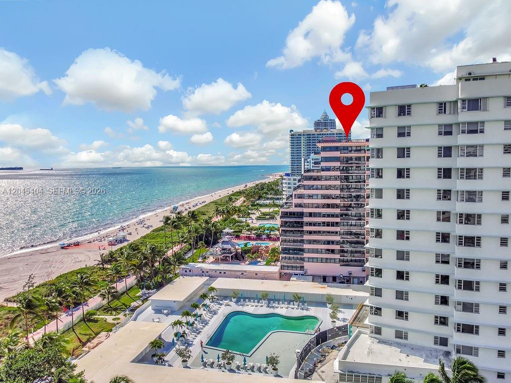 An aerial view shows a pink beachfront high-rise building with a swimming pool below — 5225 Collins Ave # 1117, Miami Beach FL 33140, MIAMI BEACH, FL