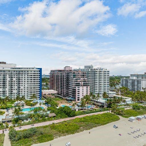 An aerial view of high-rise apartment buildings situated along a sandy beach with palm trees — 5225 Collins Ave # 1117, Miami Beach FL 33140, MIAMI BEACH, FL