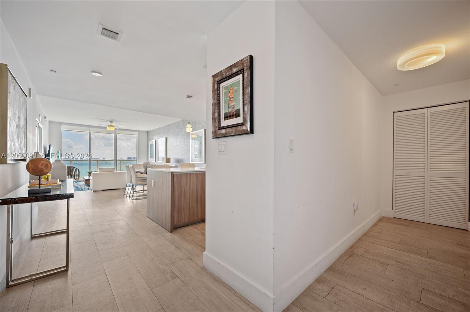 An open-concept living area features a kitchen island, tile flooring, and floor-to-ceiling ocean views — 600 NE 27th St # 1402, Miami FL 33137, MIAMI, FL