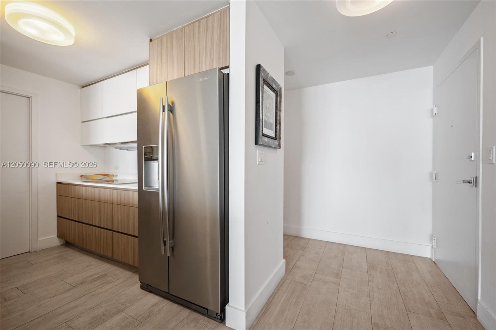 A kitchen features stainless steel appliances, wood-toned lower cabinets, and white upper cabinets — 600 NE 27th St # 1402, Miami FL 33137, MIAMI, FL