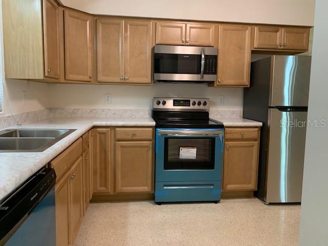 A kitchen features light wood cabinets, stainless steel appliances, and white laminate countertops — 6367 KEARCE STREET, ORLANDO, FL