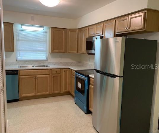 A kitchen features light wood cabinets, stainless steel appliances, and a window with blinds — 6367 KEARCE STREET, ORLANDO, FL