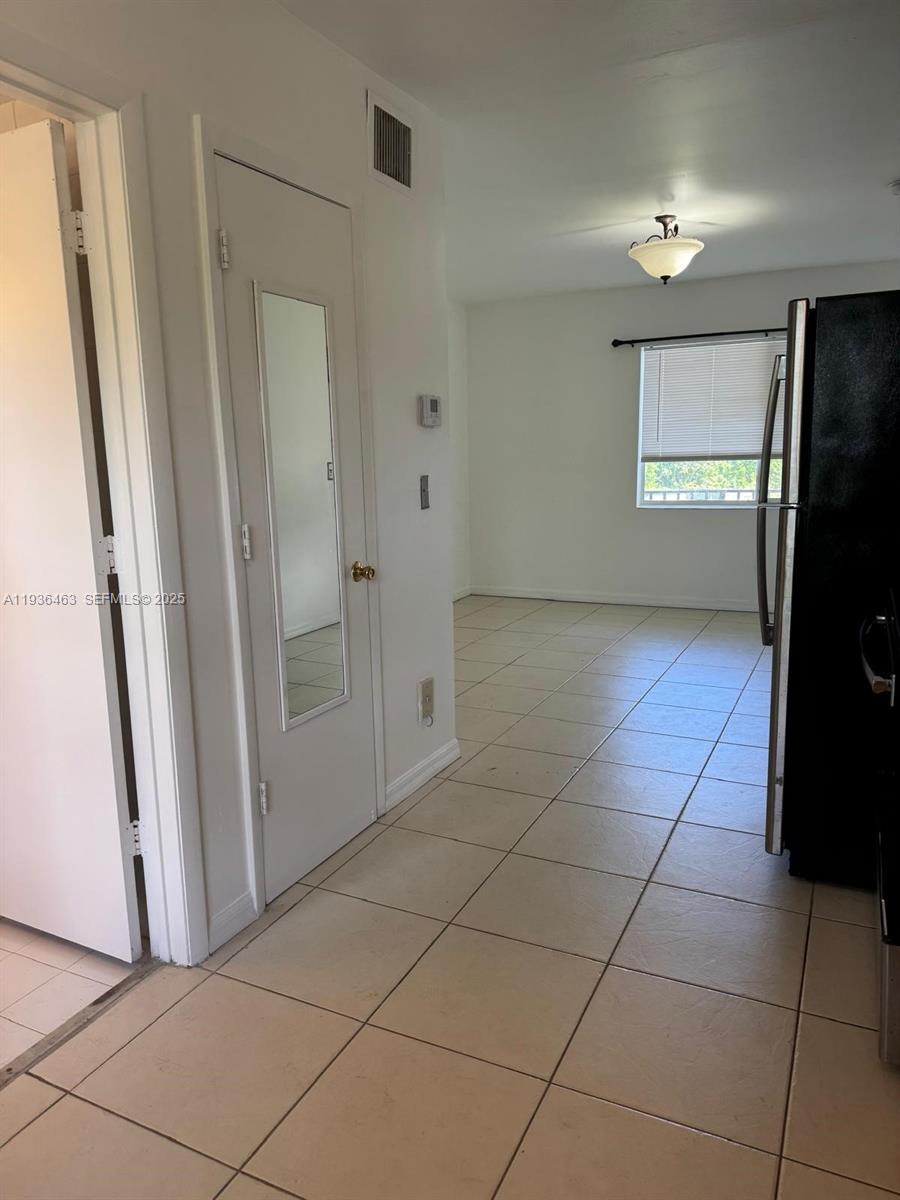 A tiled kitchen leads into a dining area with a window and a black refrigerator — 680 NE 88th Ter # 11, Miami FL 33138, MIAMI, FL
