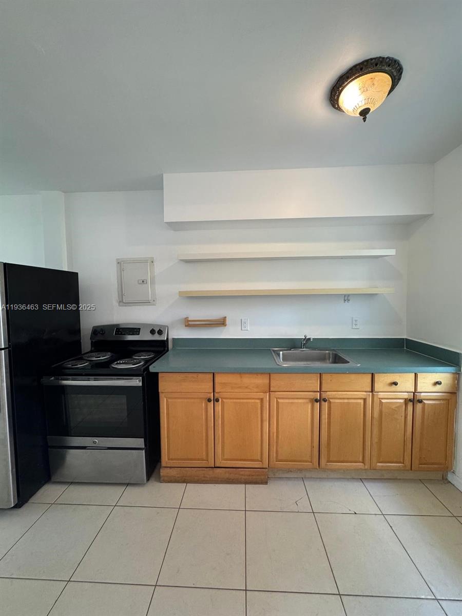 A kitchen features light wood cabinets, a green countertop, a black stove, and open shelving — 680 NE 88th Ter # 11, Miami FL 33138, MIAMI, FL