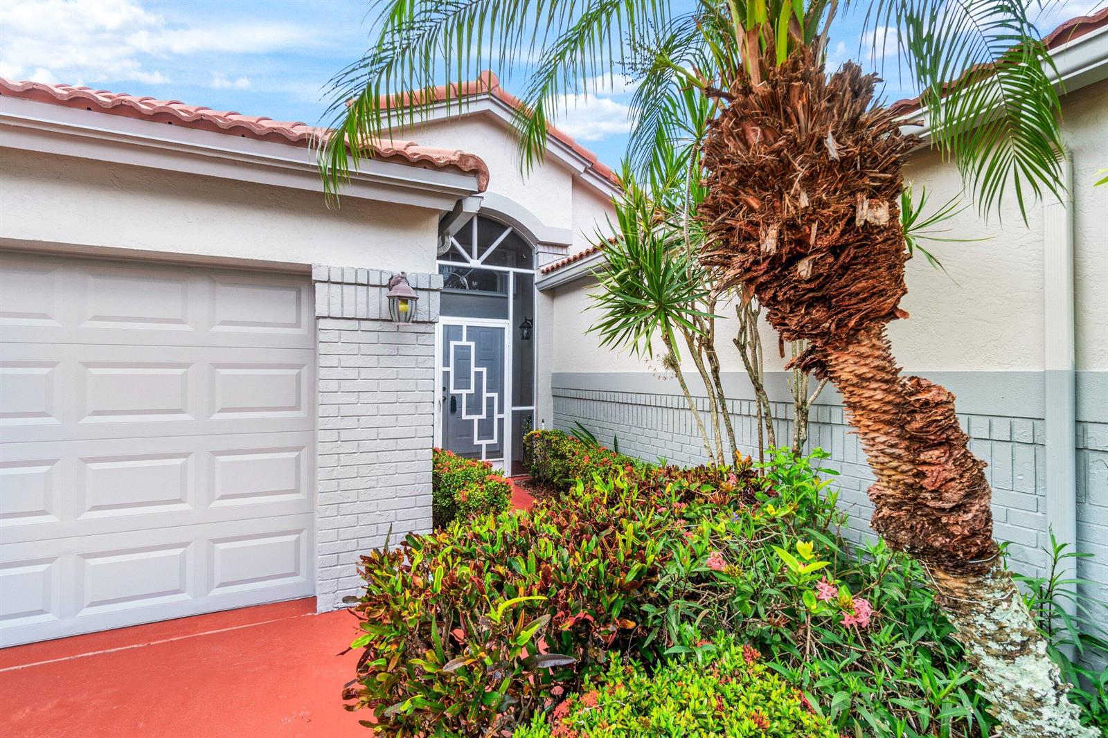 The exterior of a house features a garage, a front entrance, and a palm tree — 7851 Sailing Shores Terrace, Boynton Beach FL 33437, BOYNTON BEACH, FL