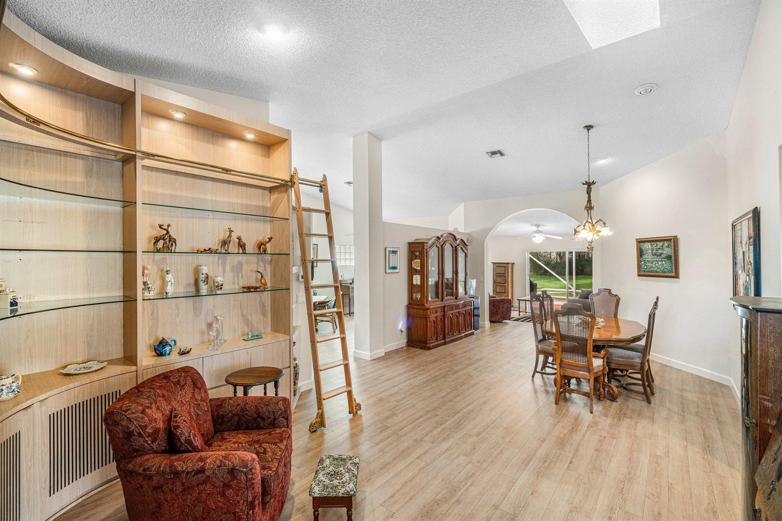 A living and dining area features wood-look flooring, a built-in bookshelf with a ladder, and furniture — 7851 Sailing Shores Terrace, Boynton Beach FL 33437, BOYNTON BEACH, FL