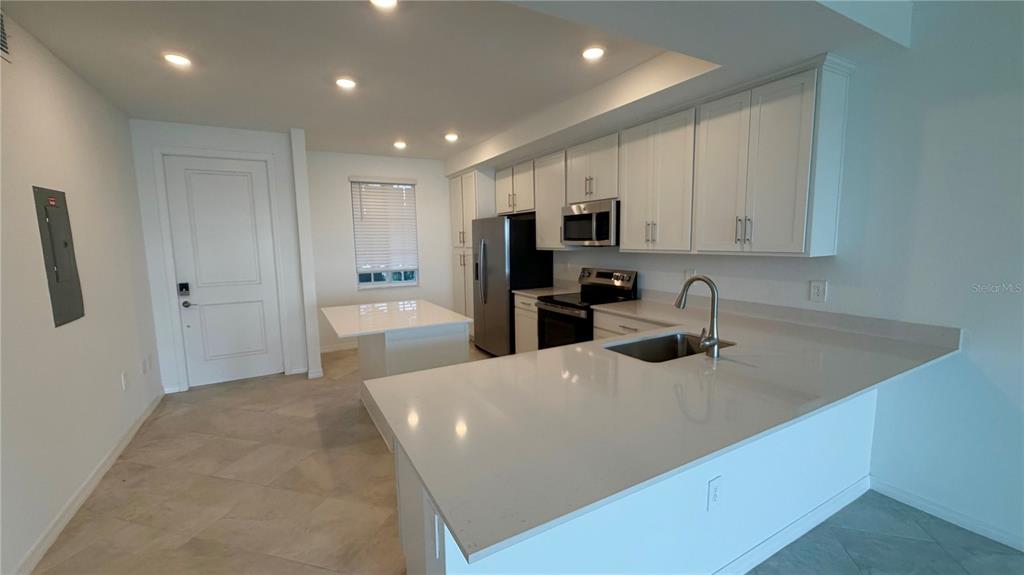 A modern kitchen features white cabinets, stainless steel appliances, and a quartz-topped island — 19116 SCALLOP LOOP UNIT 104, LAKEWOOD RANCH, FL