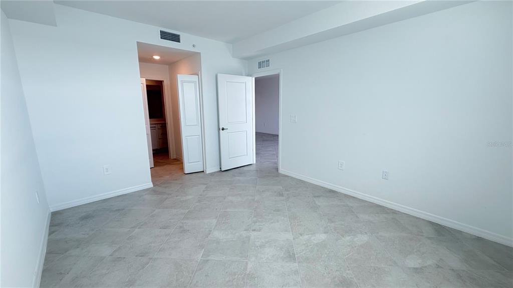 A room with light gray tile flooring, white walls, and two open doorways — 19116 SCALLOP LOOP UNIT 104, LAKEWOOD RANCH, FL