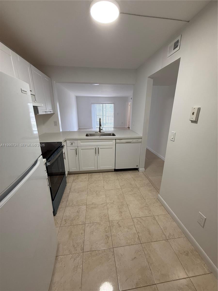 A kitchen with white cabinets, stainless steel appliances, and light-colored tile flooring — 860 NE 207th Ter # 106, Miami FL 33179, MIAMI, FL