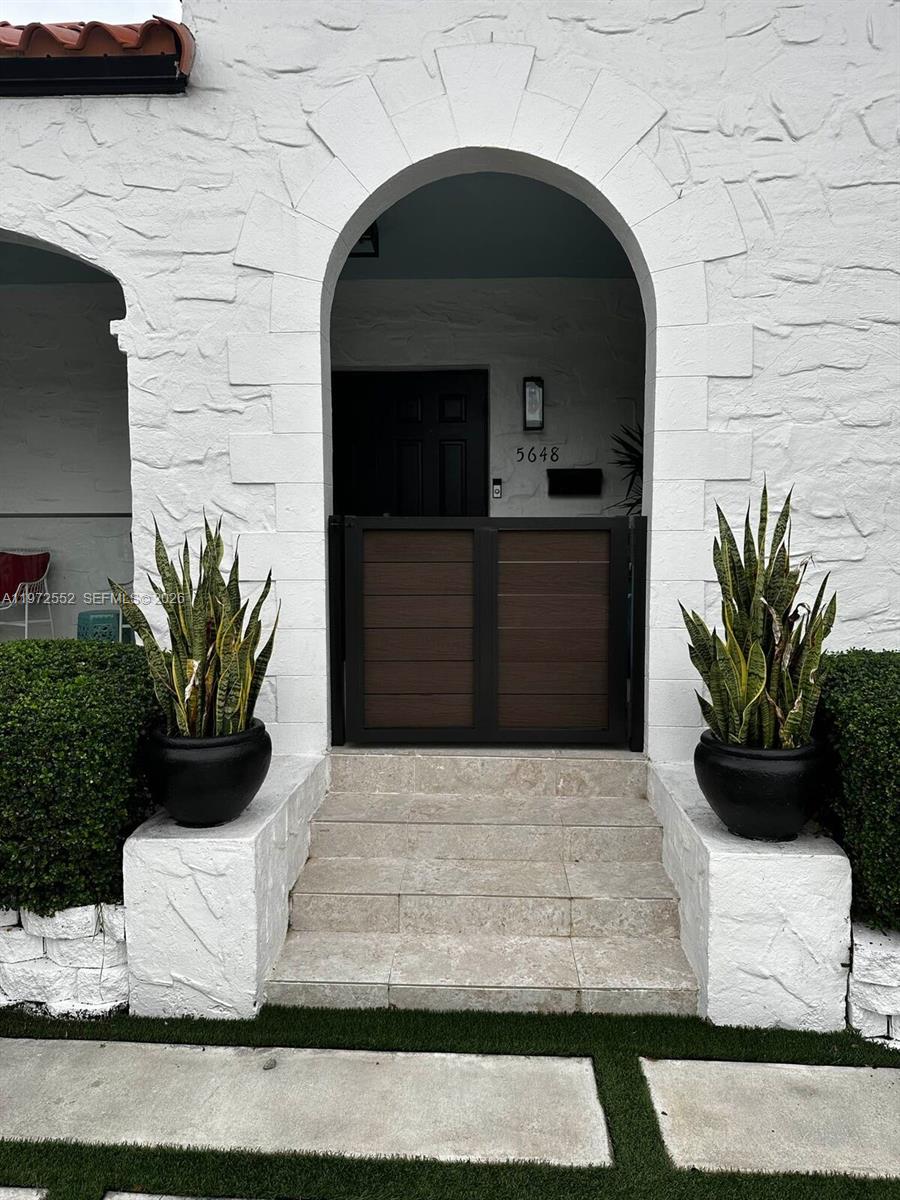 An arched entryway features a brown gate, stone steps, and two potted snake plants — 5648 SW 5th Ter, Miami FL 33134, MIAMI, FL